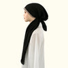 Une femme portant un foulard modal noir avec des embellissements de diamants et un haut blanc.