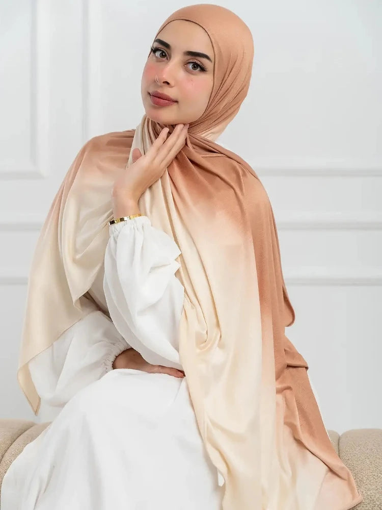 Una mujer vistiendo un pañuelo de hijab de algodón degradado beige sobre un conjunto blanco.