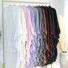 A rack of ruffled 2-layer chiffon hijabs in various pastel and earthy tones hanging on a gold stand.