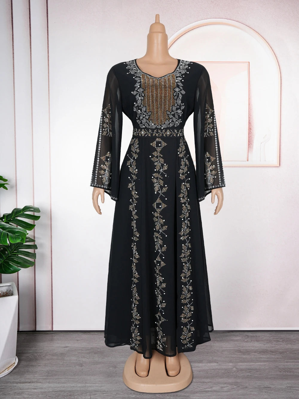 A black maxi dress with gold embroidery and sequins displayed on a mannequin.