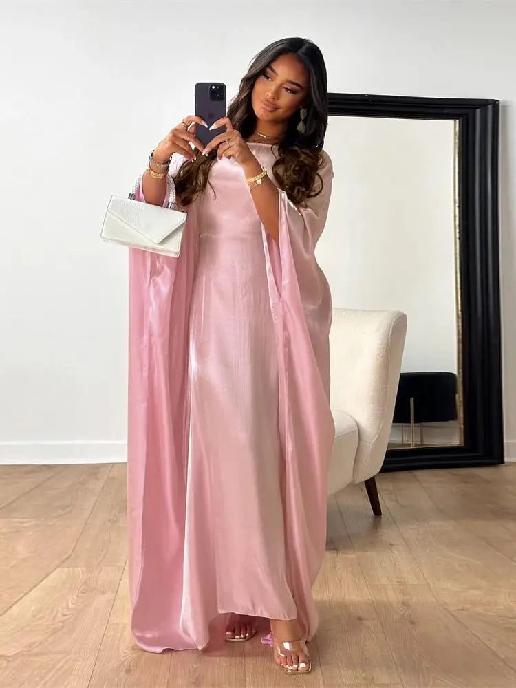 Una mujer vistiendo una abaya de satén rosa con corte batwing, tomando una selfie en el espejo.