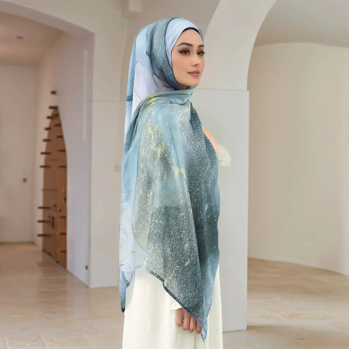 Eine Frau trägt einen eleganten bedruckten Baumwoll-Rayon-Hijabschal in blau-weißen Tönen.