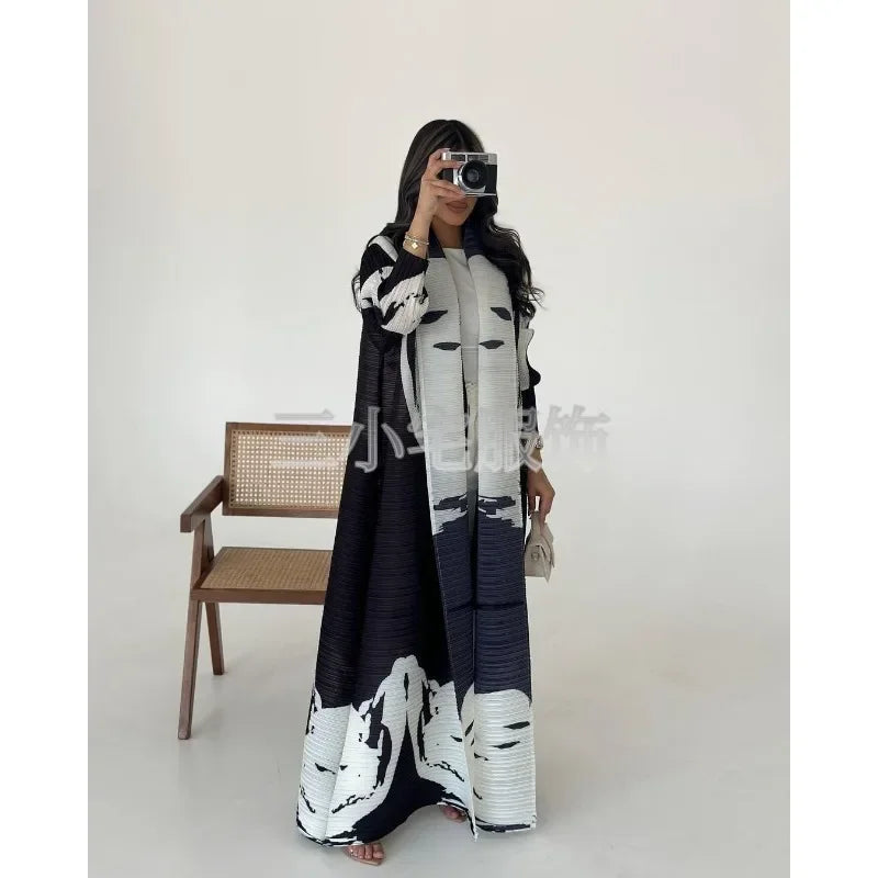 Une femme modélise une veste coupe-vent plissée à imprimé rétro noir et blanc sur un fond blanc.