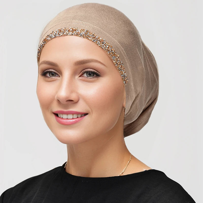 Una mujer vistiendo unhiyab elástico de algodón modal beige con ribete de lentejuelas doradas.