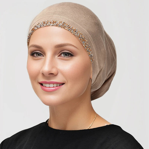 A woman wearing a beige modal cotton stretchy inner hijab with gold sequin trim.