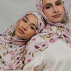 Une femme portant un hijab floral aquarelle rose et un haut crème.