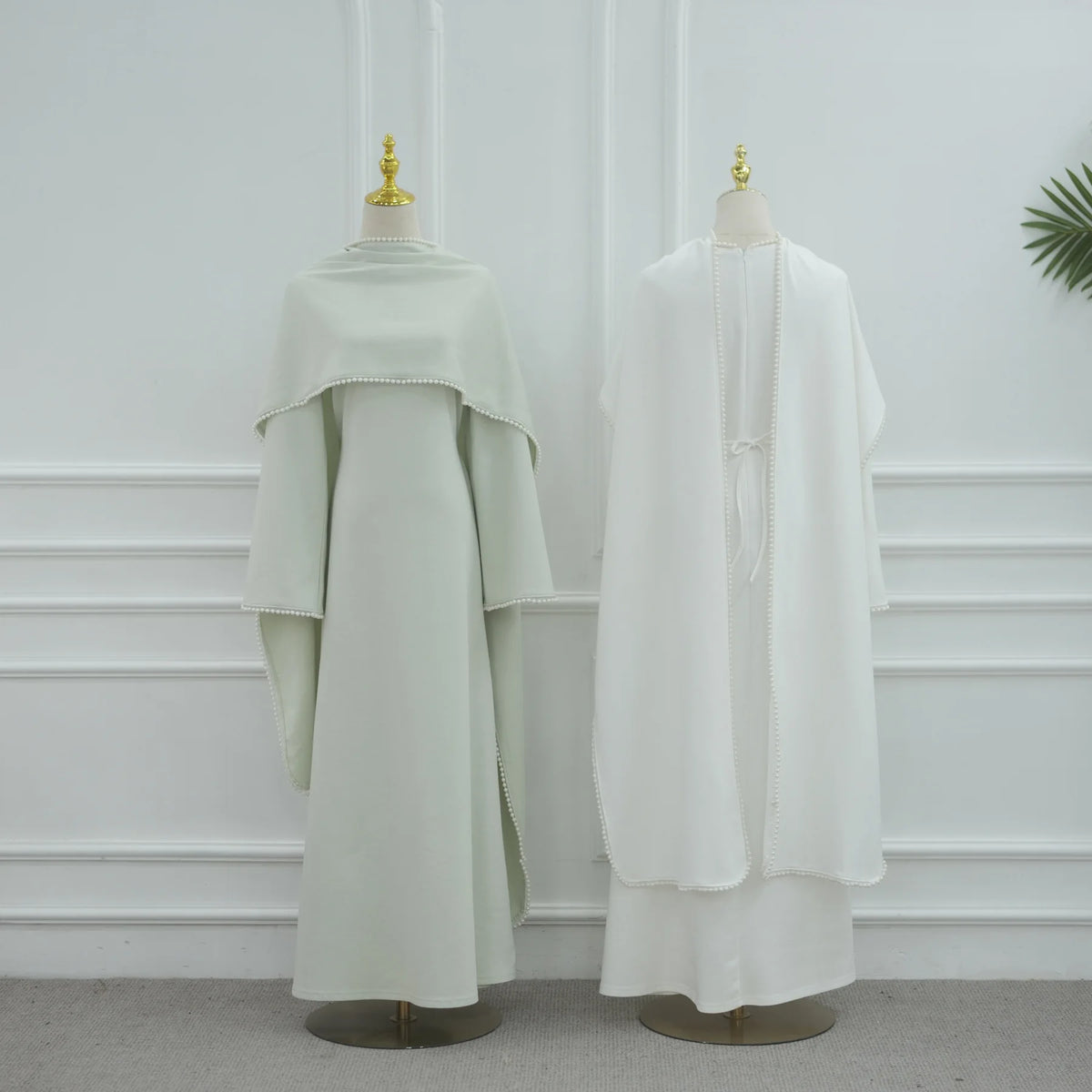 Elegantes, einfaches, weißes Abaya-Kleid auf einem Mannequin vor einer weißen Wand.