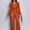 A woman models an orange ribbed knit jumpsuit with a deep V-neck and puff sleeves.