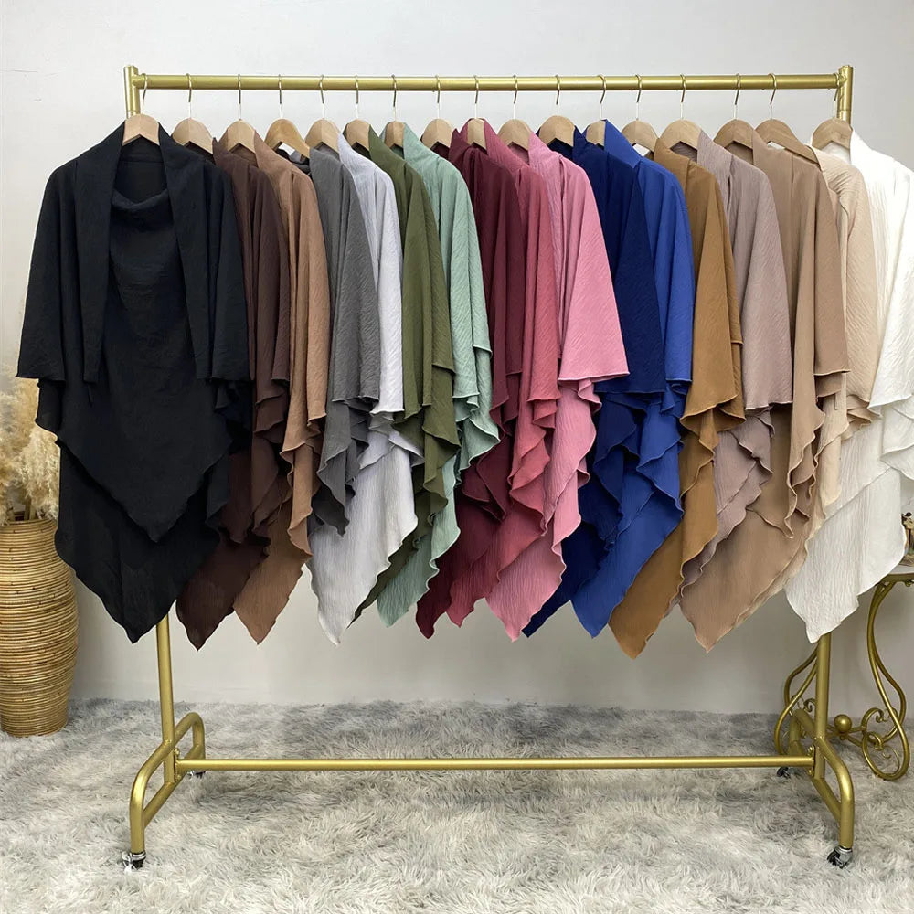 A rack of two-layer everyday hijab scarves in various muted and deep colors displayed on a gold hanger.