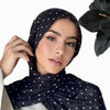 Una mujer vistiendo un hijab con bufanda de lunares negros y una blusa blanca, hecha de tela modal de doble cara.