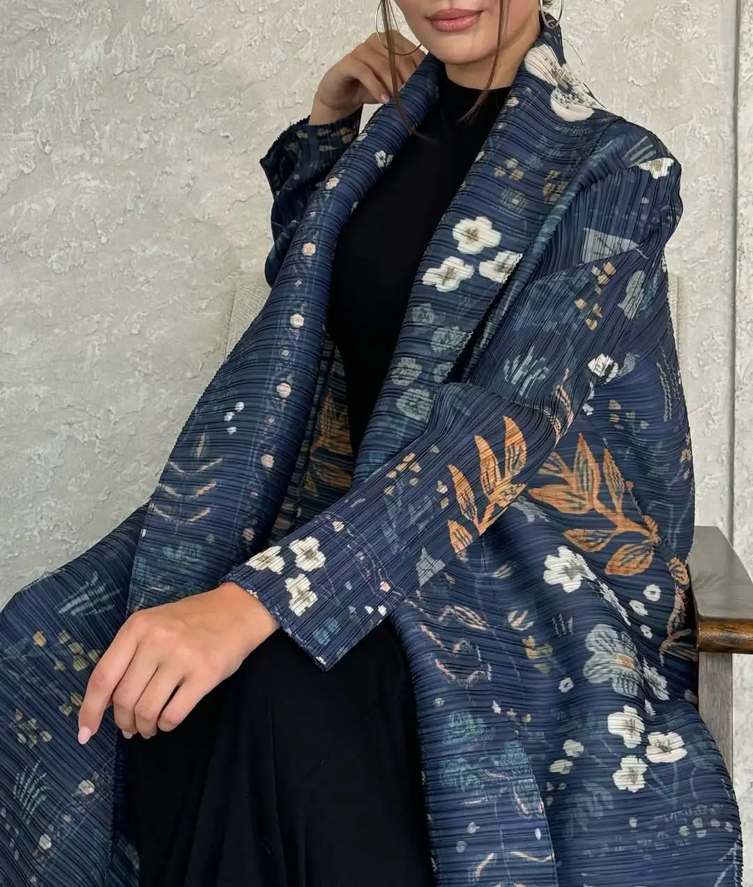 Eine Frau trägt einen fließenden, plissierten Abaya-Cardigan in dunkelblauem Muster über einem schwarzen Kleid.
