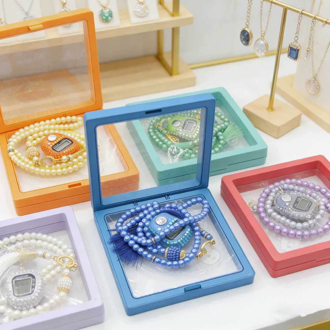 A collection of Islamic tasbih prayer beads and digital counter bracelets displayed in various wooden and colored boxes.