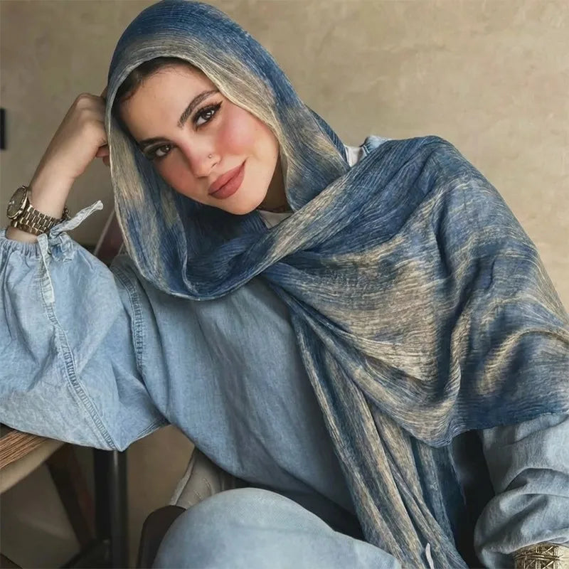 Una mujer vistiendo un pañuelo hijab estampado con acuarela azul y gris y una blusa a juego.