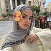Une femme portant un hijab de mousseline gris doux avec des détails en dentelle noire et un haut jaune pâle, posant à l'extér