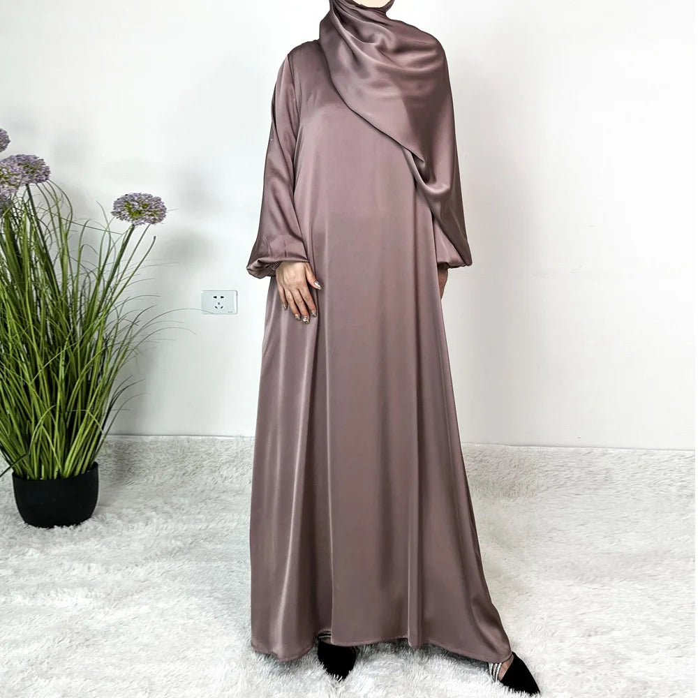 Modelo vistiendo un largo y fluido vestido maxi de satén malva y hijab a juego.