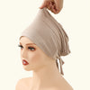A woman is shown wearing a beige adjustable elastic headband hijab cap on her head.