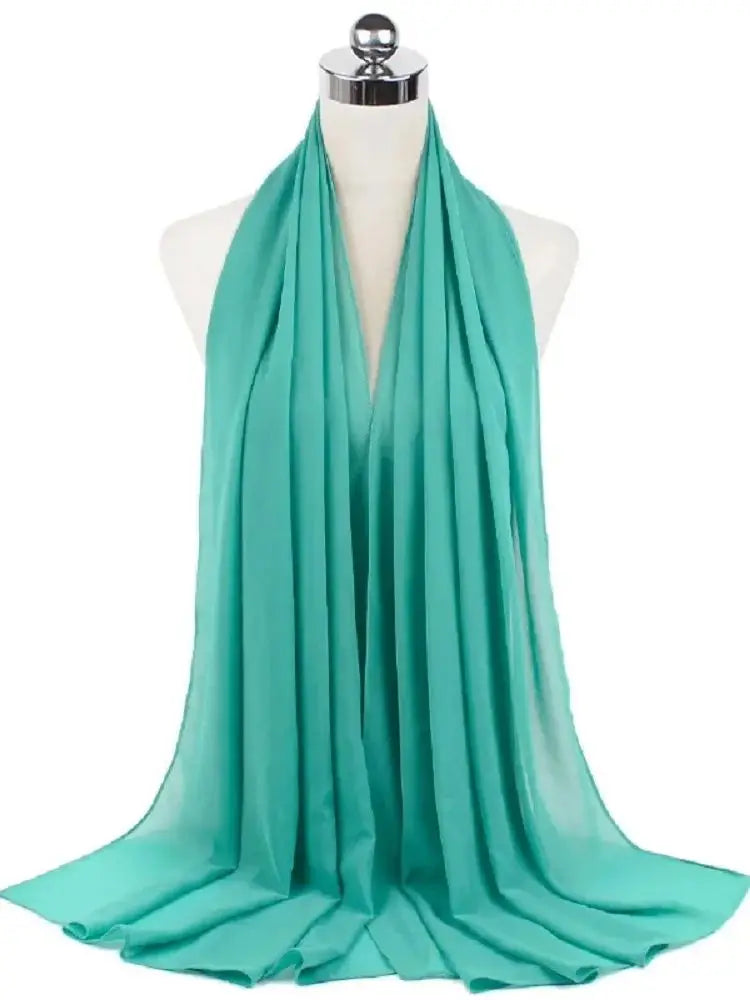 Ein türkis-durchscheinender Schal aus Chiffon, um den Hals einer Mannequin drapiert.
