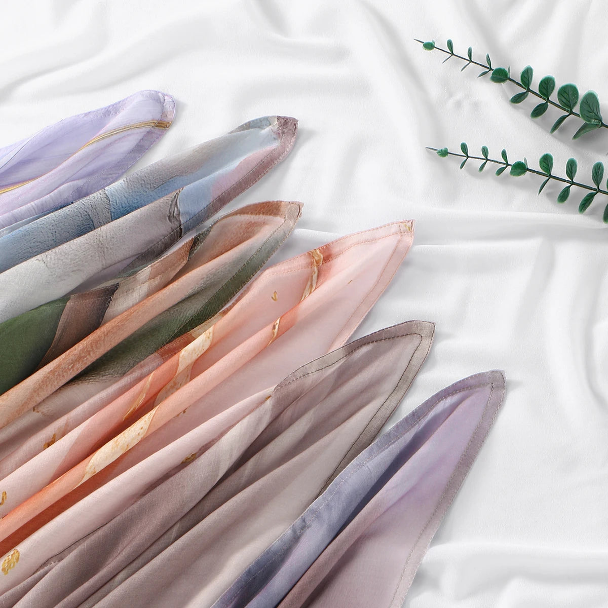 Eine Kollektion von durchscheinenden Rayon-Modal-Hijab-Schals mit Aquarell-Ombré-Mustern in Violett-, Rosa- und Grüntönen.
