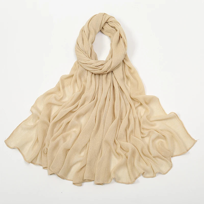Écharpe en crinkle beige drapée et pliée sur fond blanc.