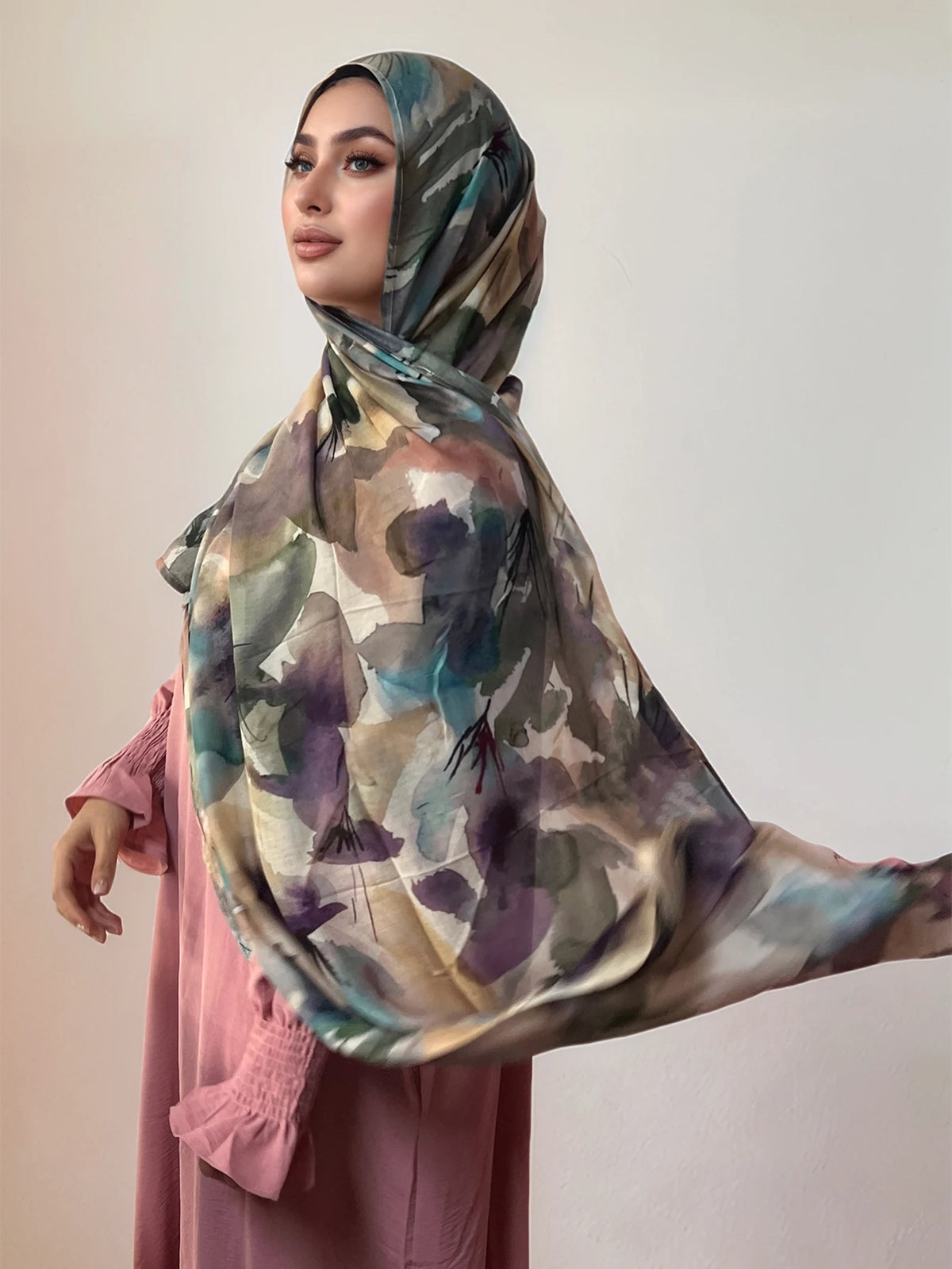 Une femme portant un foulard voile imprimé élégant dans des tons bleu sarcelle, violet et beige.