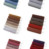 Collection de foulards et châles en tissu empilés dans diverses nuances de gris, marron, rose et violet.