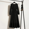 Schwarzes Boho-Blumenmuster-Maxikleid an einem Holzstab vor einer weißen Wand