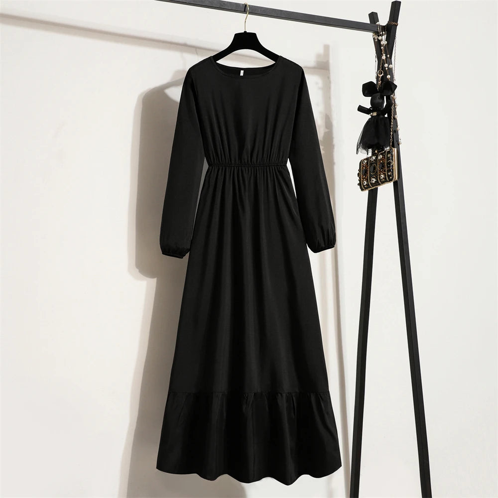 Schwarzes Boho-Blumenmuster-Maxikleid an einem Holzstab vor einer weißen Wand