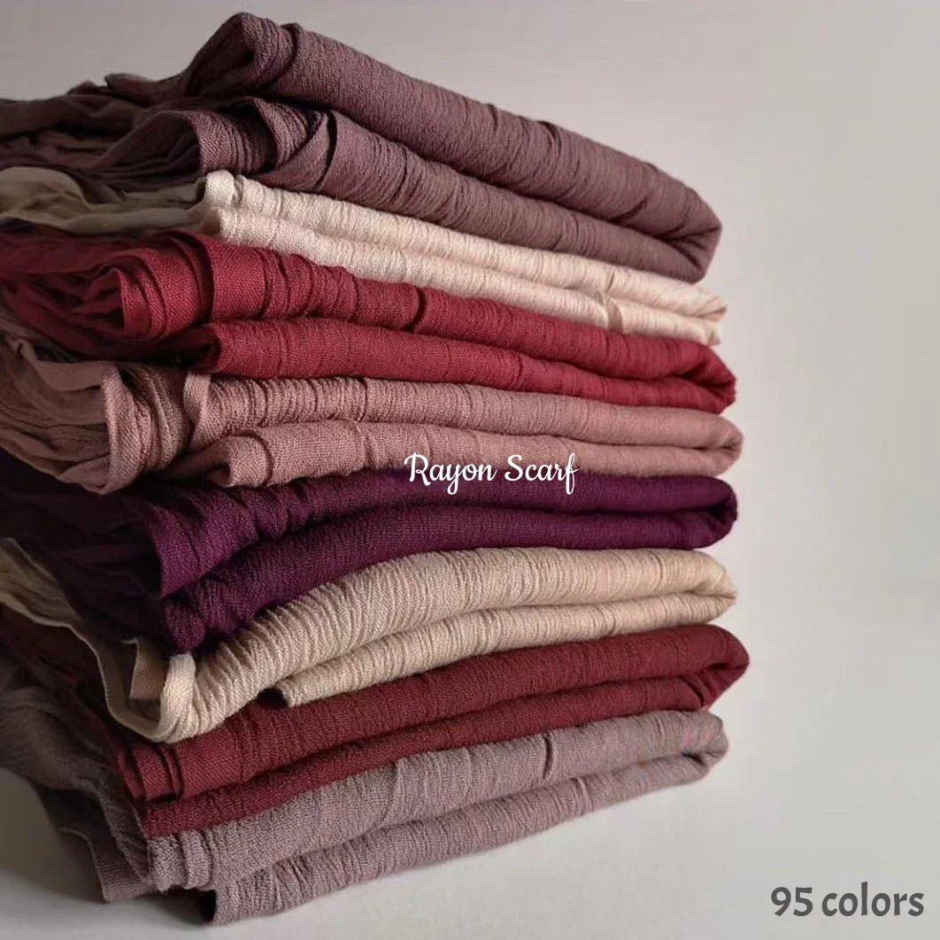 Une pile de 95 foulards hijab en coton viscose doux dans diverses nuances de rose, mauve et bordeaux.