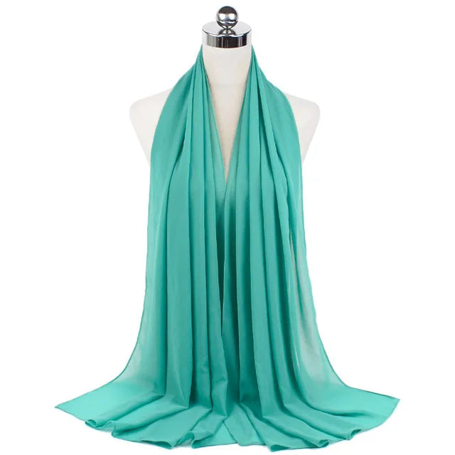 A teal chiffon hijab scarf draped around a mannequin neck.