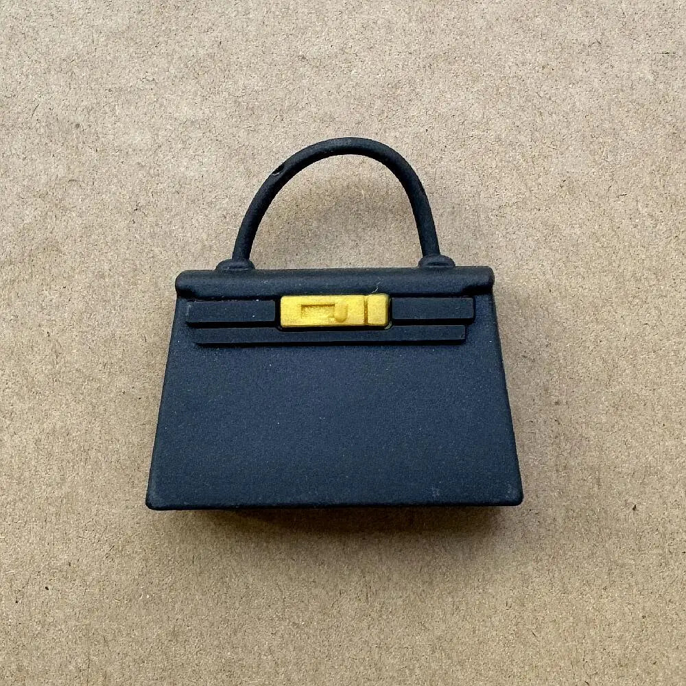 Bolso de cuero azul marino oscuro con hebilla dorada y asa negra.