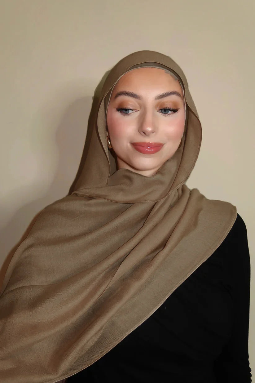 Eine Frau trägt einen einfarbigen braunen Gradient-Rayon-Modalfach-Hijab mit hohem Ausschnitt.