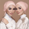 Deux femmes portent des hijabs doubles en satin rose et des hauts assortis en satin.