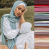 A woman wearing a soft mint green chiffon hijab scarf and white blouse, looking directly at the camera.