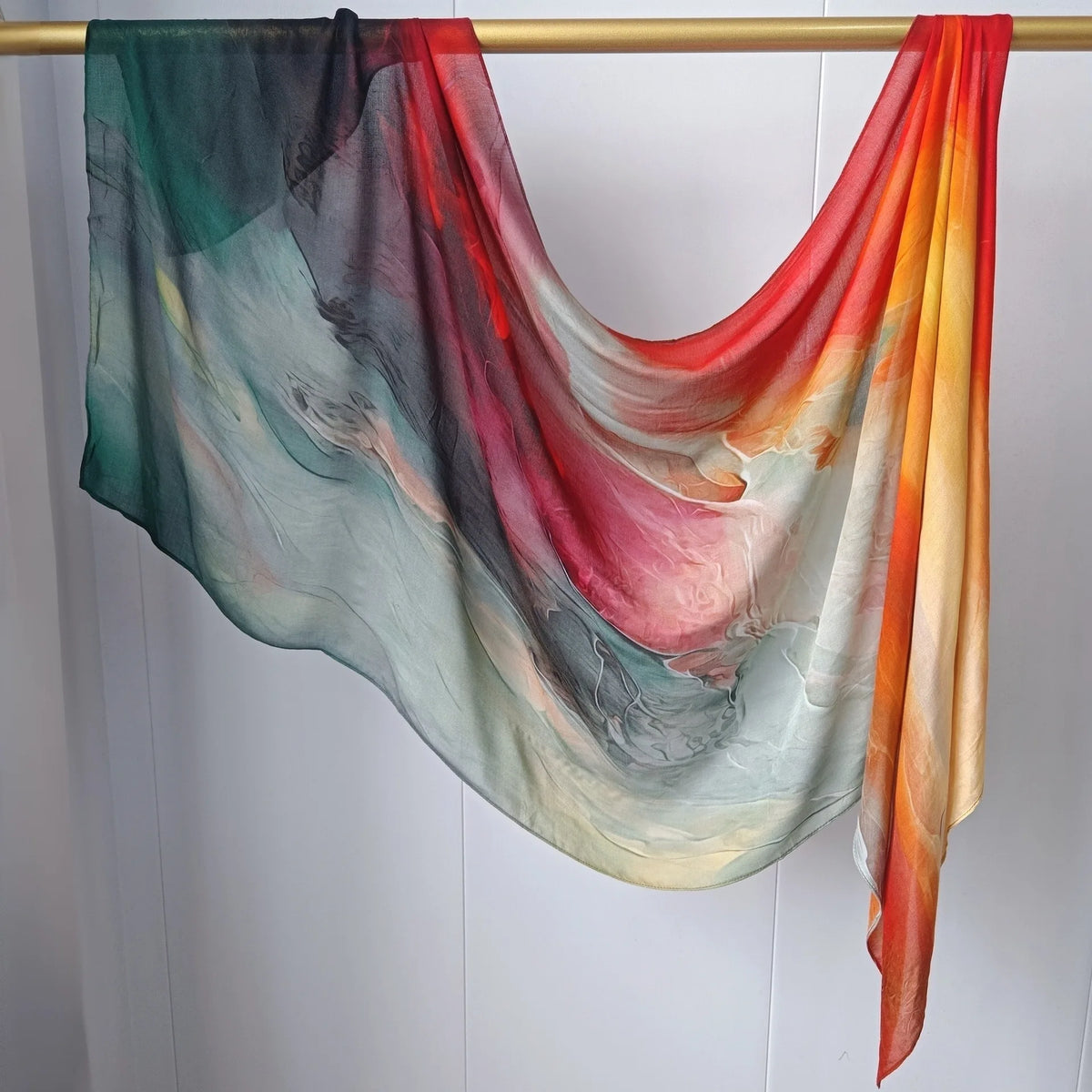 Fließender mehrfarbiger Hijab-Schal über einem Holzhaken vor weißem Hintergrund.