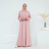 Una mujer vistiendo un vestido rosa abaya fluido para la oración contra un fondo blanco.
