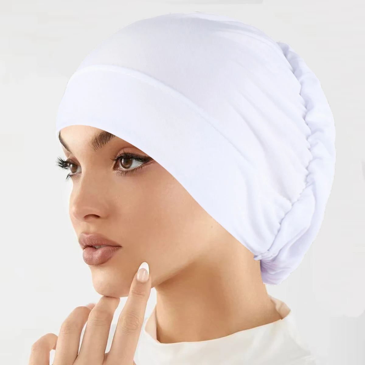 Eine Frau trägt eine weiße Stretch-Turbanmütze auf dem Kopf.
