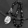 Porte-clés islamiques arabes en perles noires et argentées sur une surface sombre.