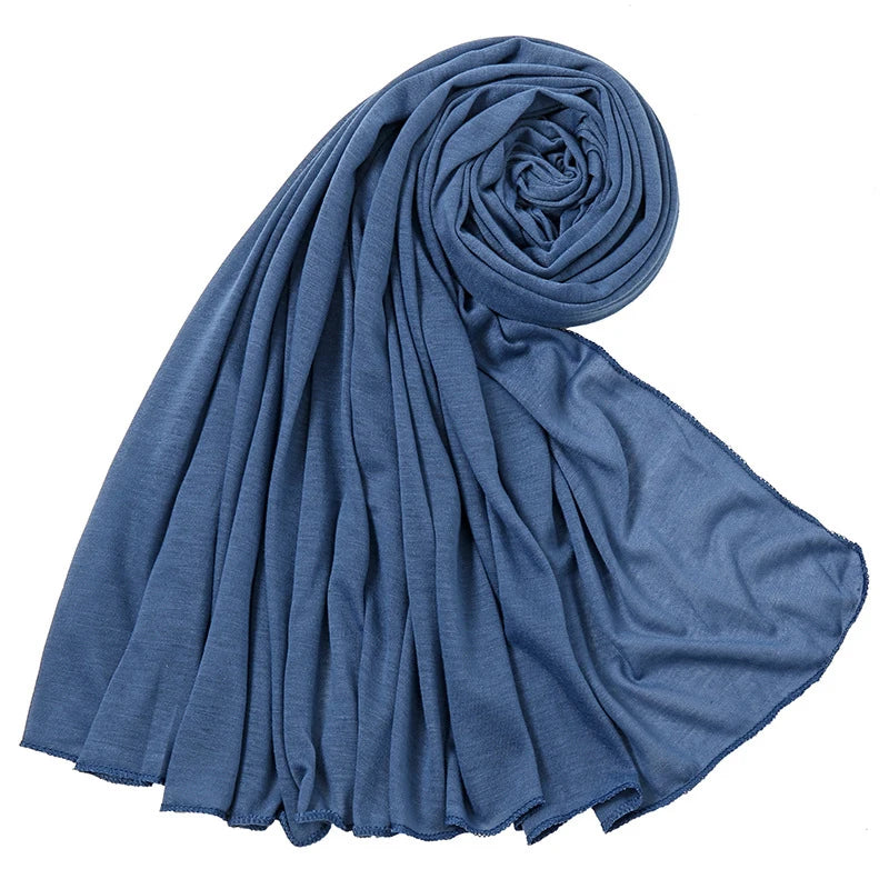Ein tiefblauer, einfacher Baumwollstrickschal in spiralförmiger Wicklung.