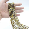 Una mano sostiene una hebra de cuentas de vidrio marrón y beige usadas para el tasbih islámico.