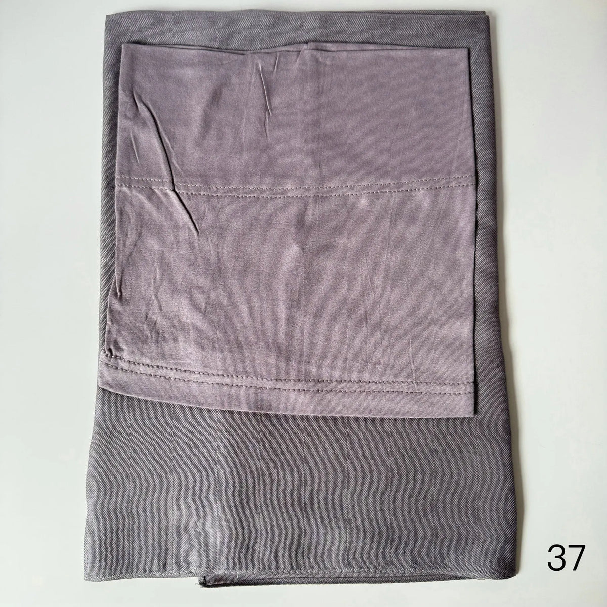 A folded soft lilac gray hijab set made of modal rayon fabric.