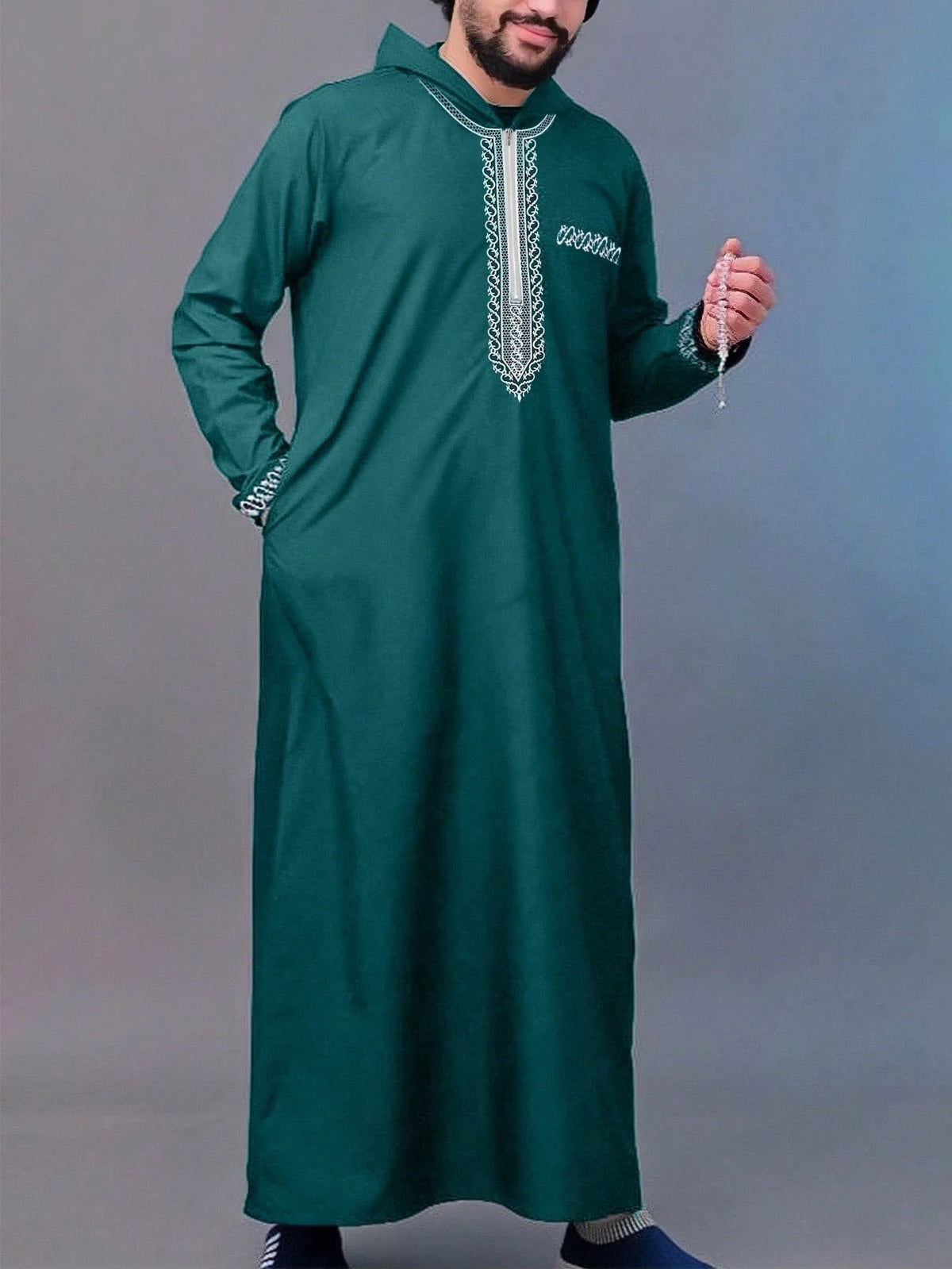 A man wearing a dark green Moroccan ethnic thobe with a stand collar and silver embroidery.
