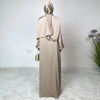 Vestido maxi de satén beige con hiyab a juego, mostrado contra una pared blanca.
