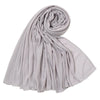 Un foulard hijab en jersey de coton gris clair, roulé et drapé, montrant sa texture fluide.