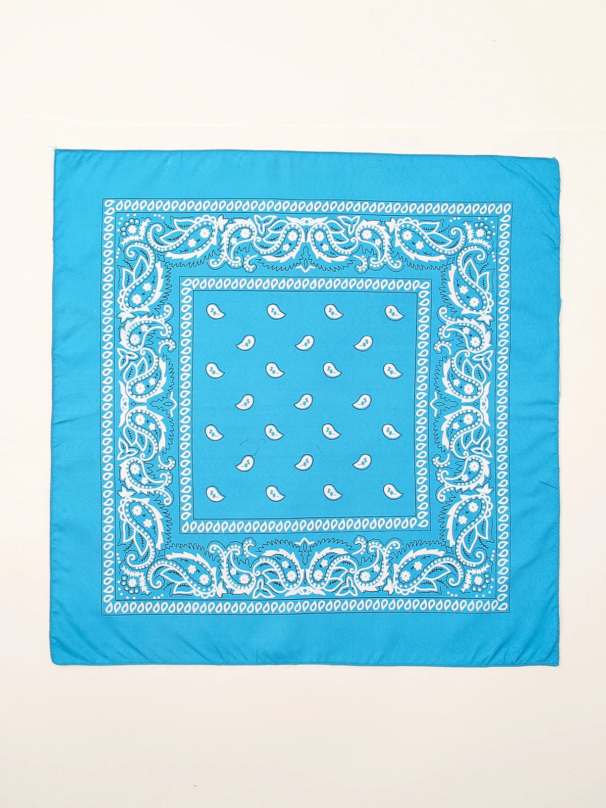 Un tissu bleu carré avec des motifs paisley blancs complexes et un motif central carré.