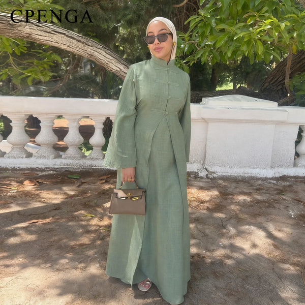 A woman wearing an elegant two-piece Arabic modest set in sage green and white, standing outdoors.
