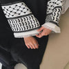Gros plan sur une manche d'abaya noire avec broderie géométrique blanche et ourlet blanc.