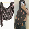 Eine Frau trägt einen dunkelbraunen floral gemusterten Hijab-Schal über Kopf und Schulter.