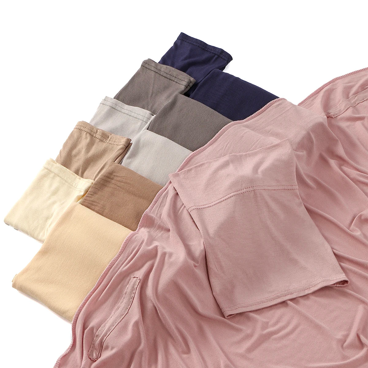 Ein Stapel verschiedenfarbiger Modals-Hijabs und ein rosa Hemd werden präsentiert.