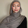 Eine Frau trägt einen einfarbigen grauen Gradient-Rayon-Hijab und schwarze Kleidung.