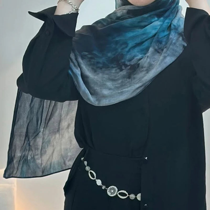 Eine Frau trägt ein dunkles Shirt und einen blau-floralen Aquarellschal um den Hals.